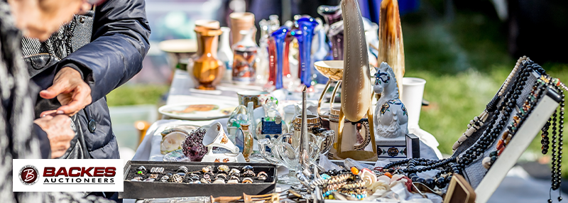 Image for Two individuals browsing table of housewares and jewelry for sale.