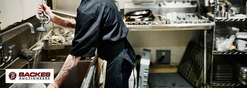 Image for Smiling female dishwasher working at sink in restaurant kitchen.